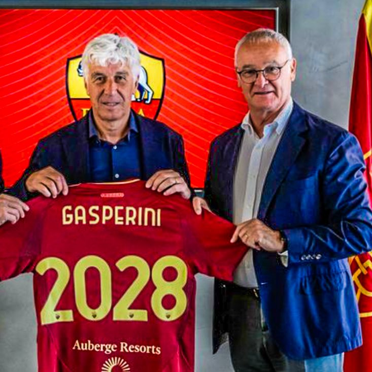 Gian Piero Gasperini holding up an AS Roma shirt and smiling after signing his contract with the club.