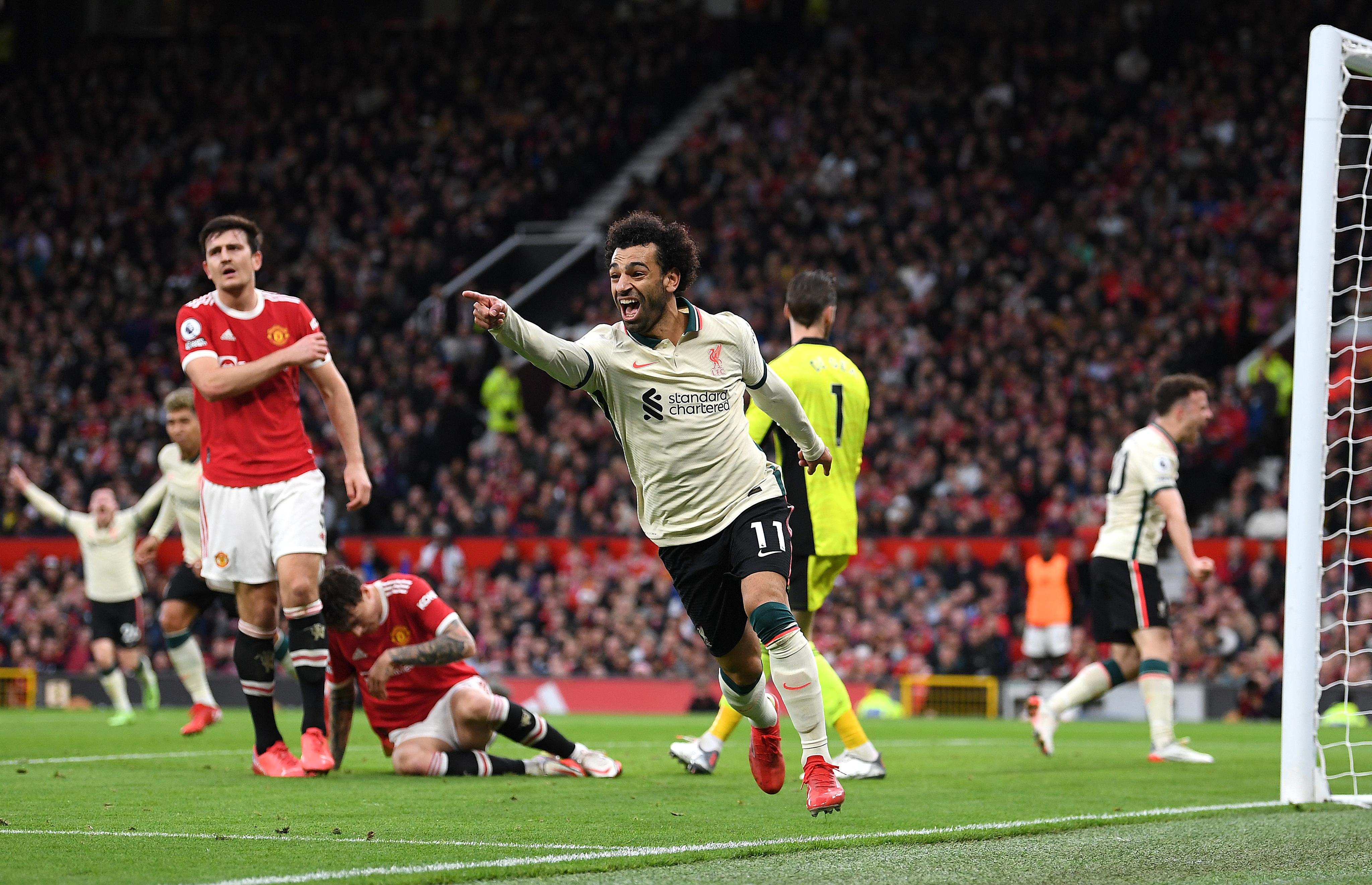 Mohamed Salah celebrates after scoring a goal against Liverpool, with Harry Maguire visible in the background.
