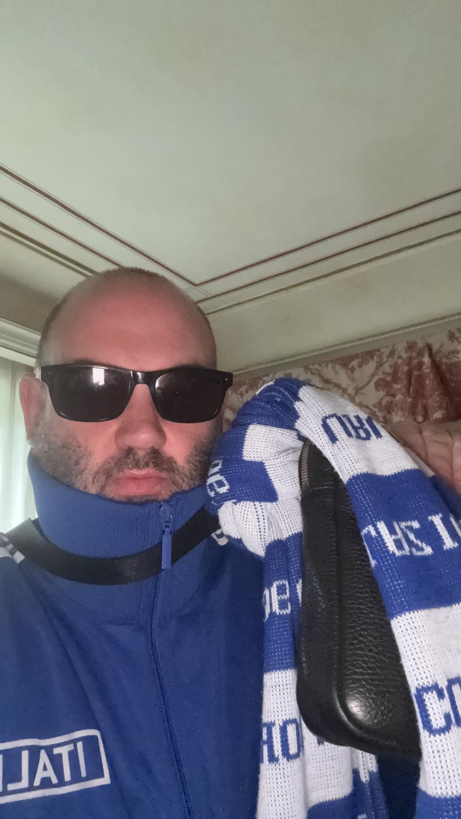 Scott posing in his hotel room holding a Lazio scarf proudly, preparing for matchday.