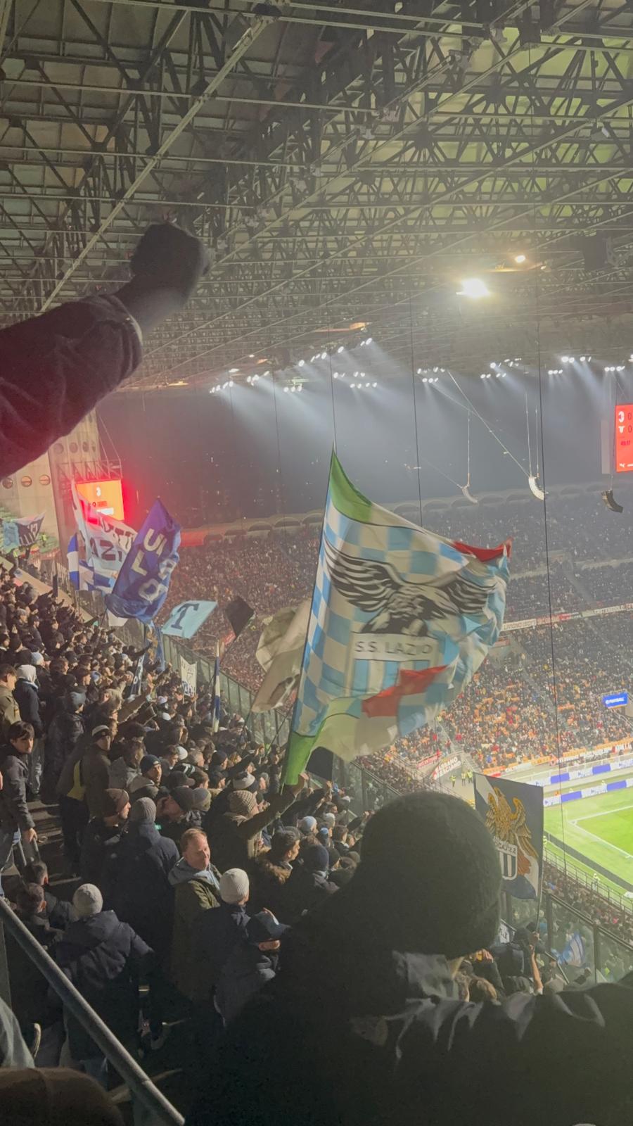 Lazio fans packed into the away sector at San Siro during the Milan vs Lazio match, waving flags and creating a vibrant blue-and-white display high in the terzo anello