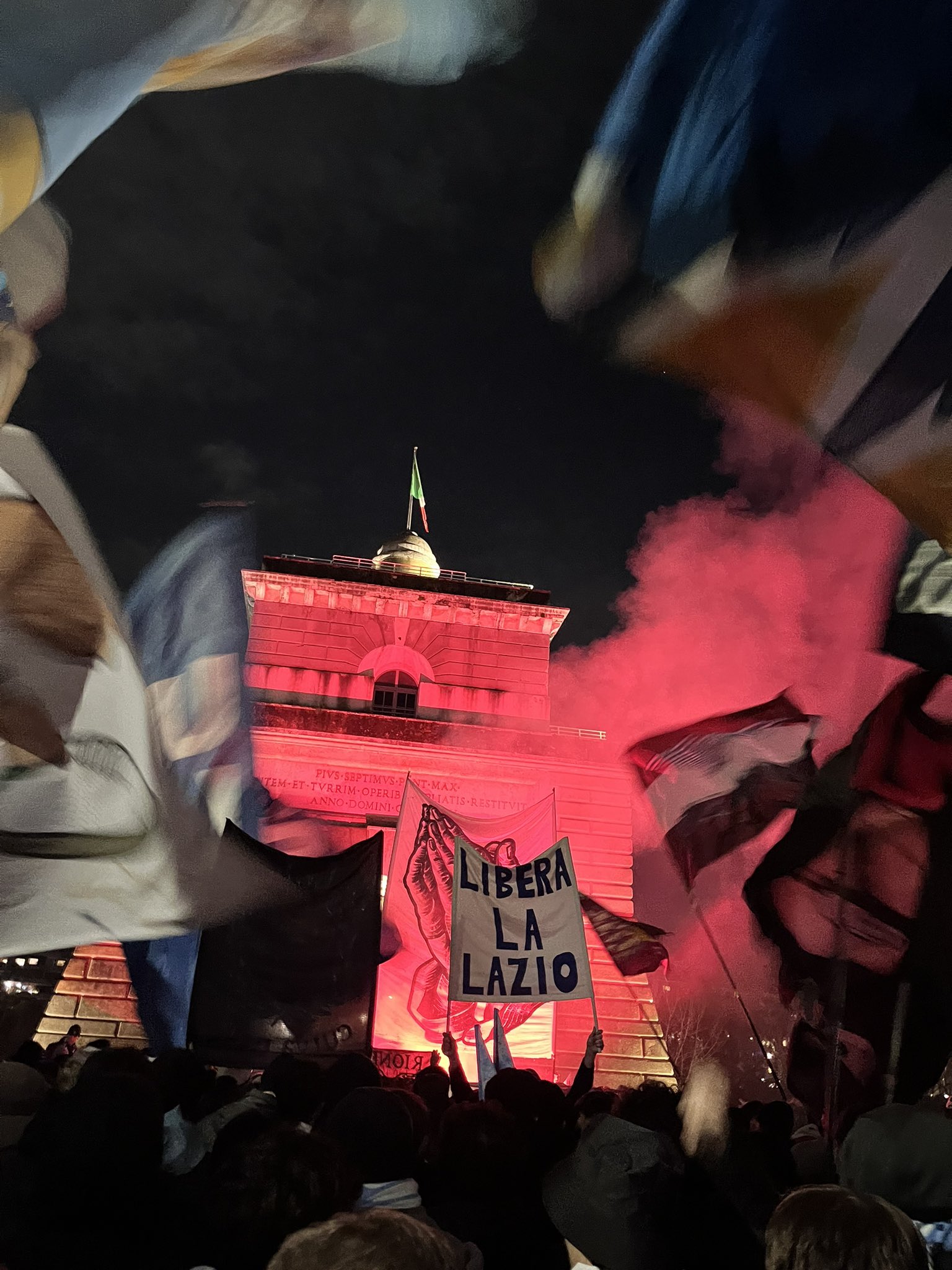 Lazio fans gathered at Ponte Milvio in Rome holding banners and flags as they protest against Claudio Lotito’s ownership, with supporters standing together near the bridge before kick-off.