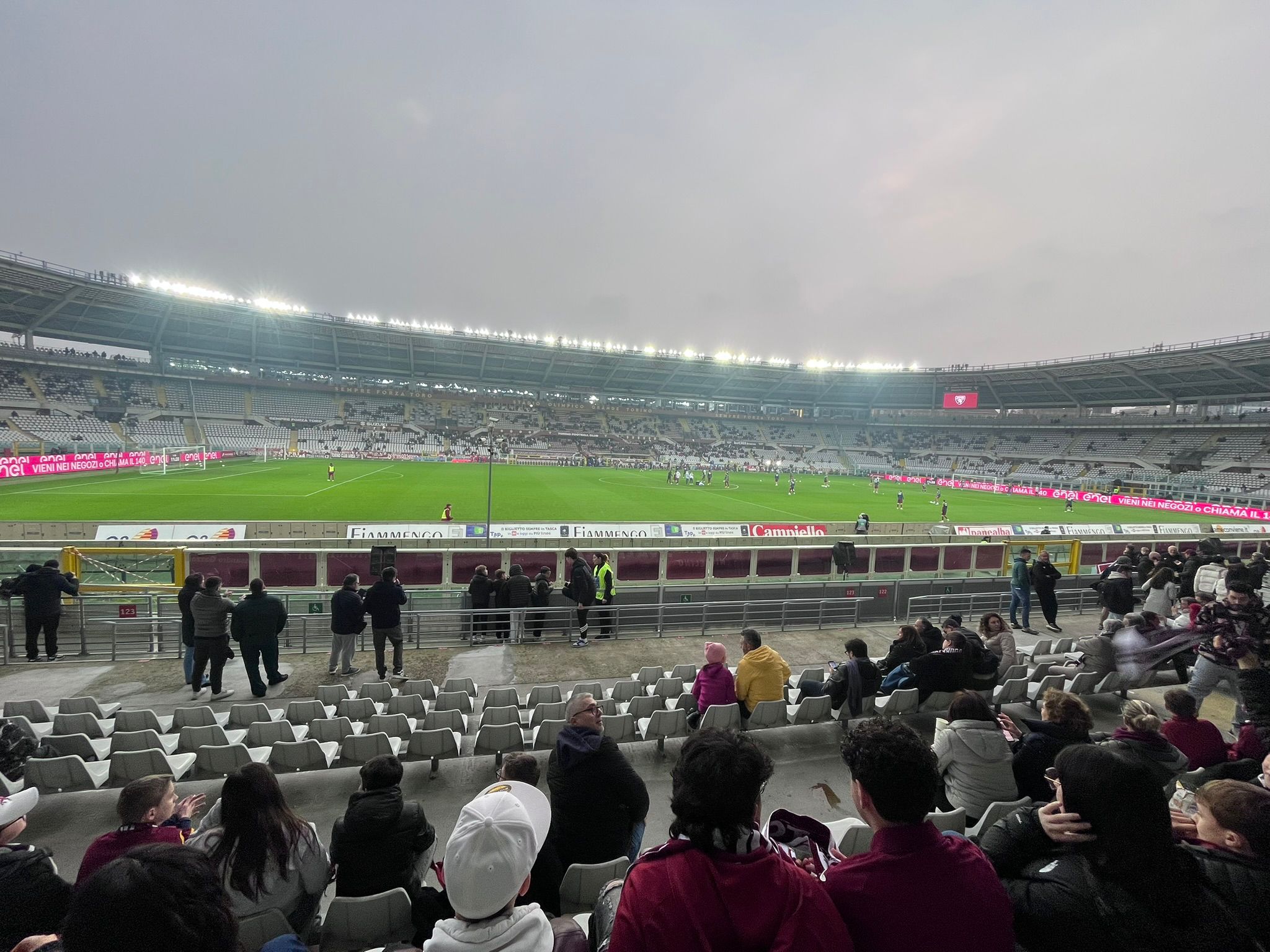 A wide crowd shot inside the Stadio Olimpico Grande Torino during Torino vs Lazio, showing sections of Torino supporters filling the stands with banners and flags while the pitch is visible below during the Serie A match.